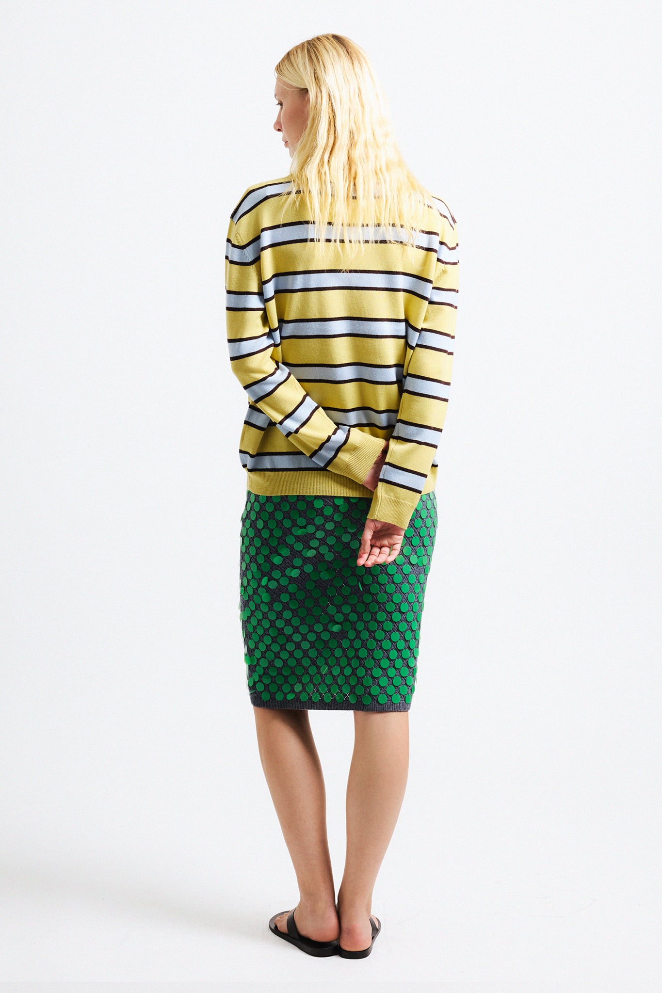 Link to "Ryan" sweater. Image is of a female model wearing yellow and grey striped polo with green sequin midi skirt.