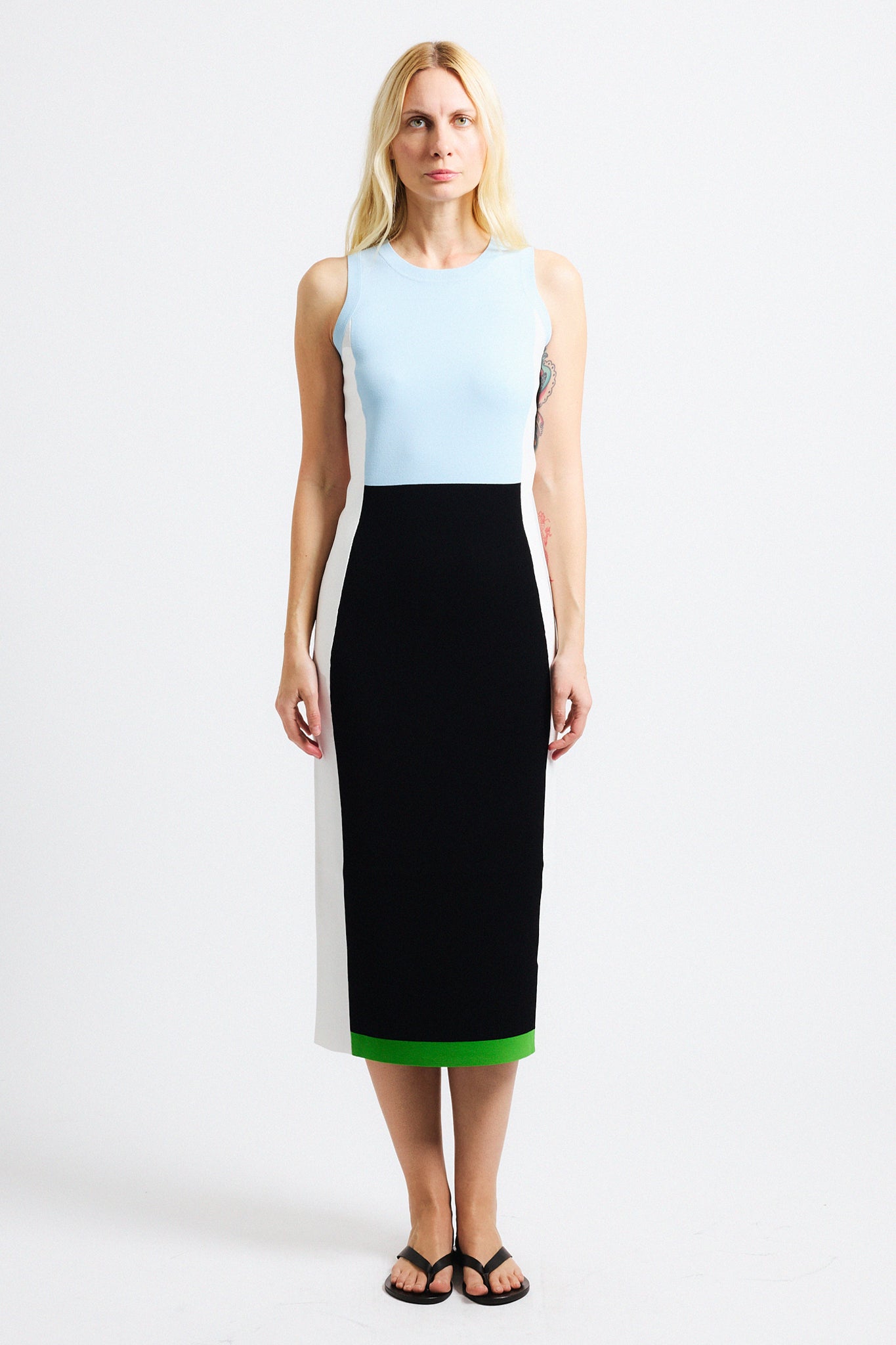Link to "Daniella" dress. Image is of a female model wearing crewneck sleeveless colorblock dress. Pattern in baby blue along chest into a black on the waist and legs, ending on a wide green hem. Back of the dress is white.